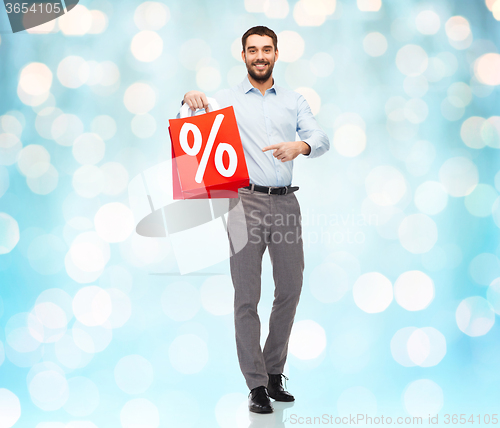 Image of smiling man with red shopping bag over blue lights