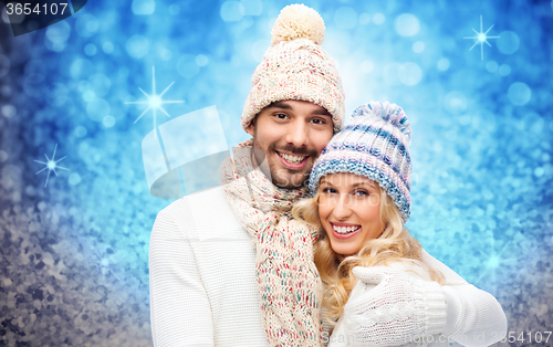 Image of happy couple in winter clothes hugging over lights