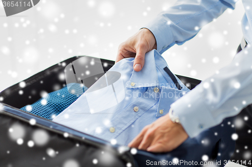 Image of businessman packing clothes into travel bag