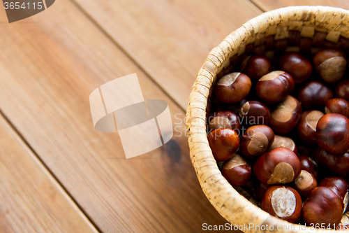 Image of close up of chestnuts in basket on wooden table