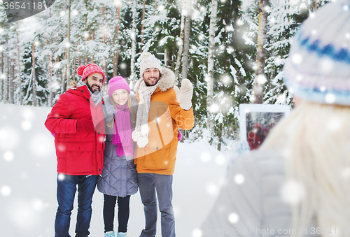 Image of smiling friends with tablet pc in winter forest