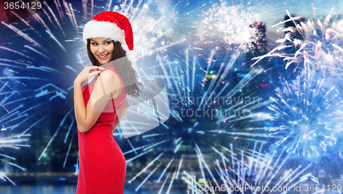 Image of woman in santa hat and red dress over firework