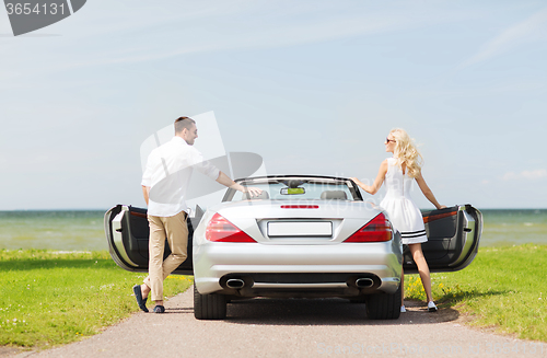 Image of happy man and woman near cabriolet car at sea