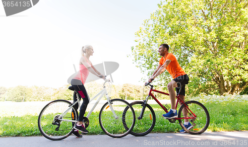 Image of happy couple riding bicycle outdoors