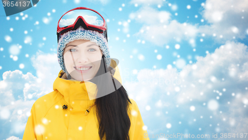 Image of happy young woman in ski goggles over blue sky