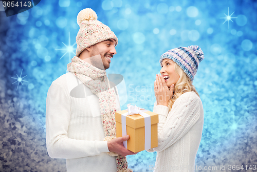 Image of smiling couple in winter clothes with gift box