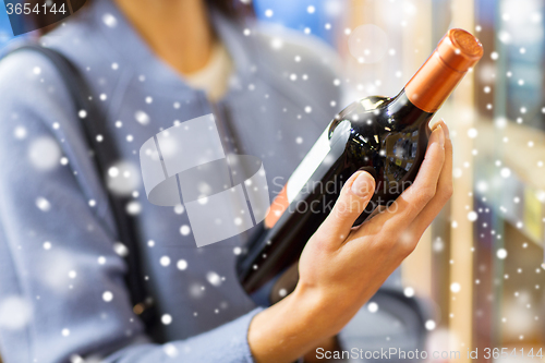 Image of happy woman choosing and buying wine in market