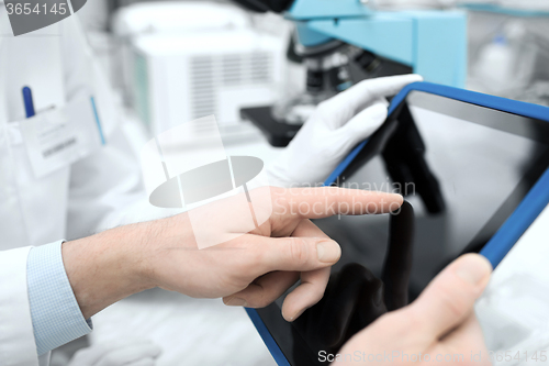 Image of close up of scientists hands with tablet pc in lab