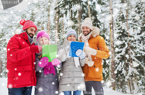 Image of smiling friends with tablet pc in winter forest