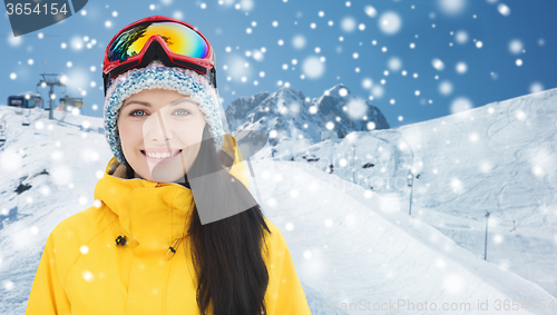 Image of happy young woman in ski goggles over mountains