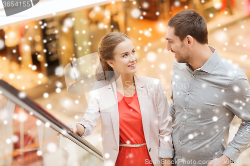 Image of couple with shopping bags on escalator in mall