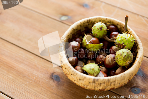 Image of close up of chestnuts in basket on wooden table