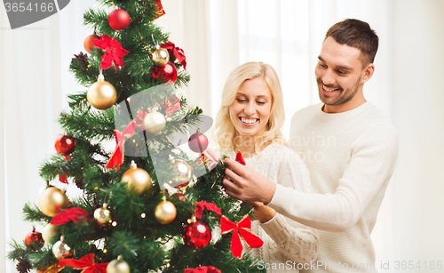 Image of happy couple decorating christmas tree at home