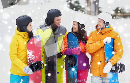 Image of happy friends in helmets with snowboards talking