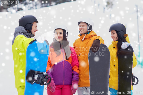 Image of happy friends in helmets with snowboards talking