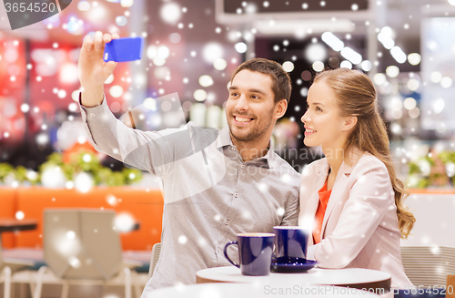 Image of happy couple with smartphone taking selfie in mall