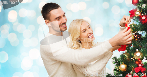 Image of happy couple decorating christmas tree at home