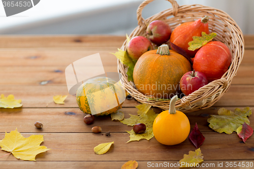 Image of close up of pumpkins in basket on wooden table