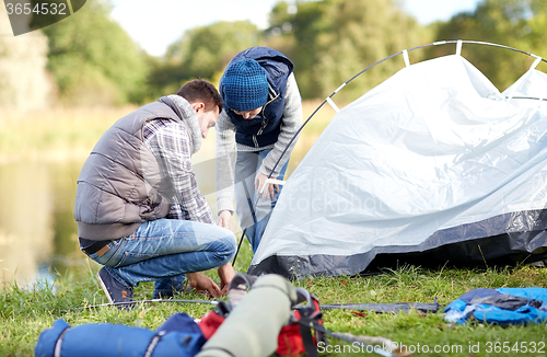 Image of happy father and son setting up tent outdoors