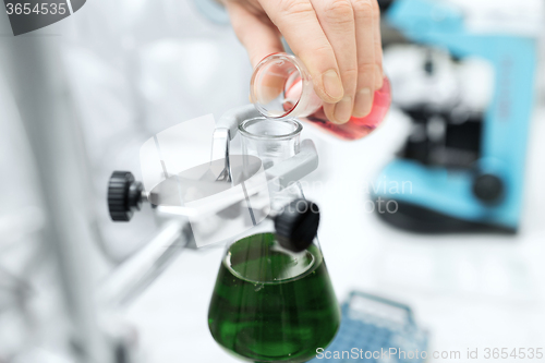 Image of close up of scientist filling test tubes in lab