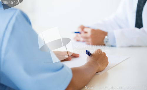 Image of close up of doctor taking notes at hospital