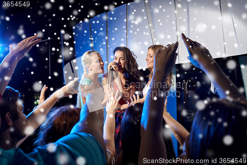 Image of happy young women singing karaoke in night club