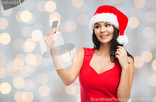 Image of woman in santa hat taking selfie by smartphone