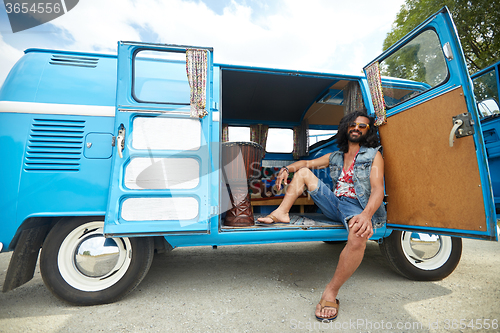Image of smiling young hippie man in minivan car
