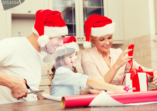 Image of smiling family in santa helper hats with gift box