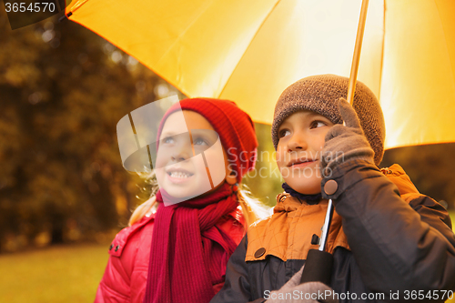 Image of happy boy and girl with umbrella in autumn park