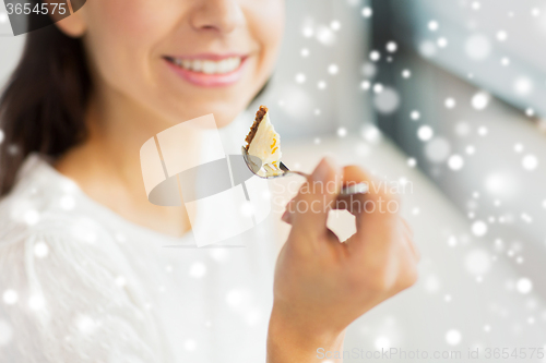 Image of close up of woman eating cake at cafe or home