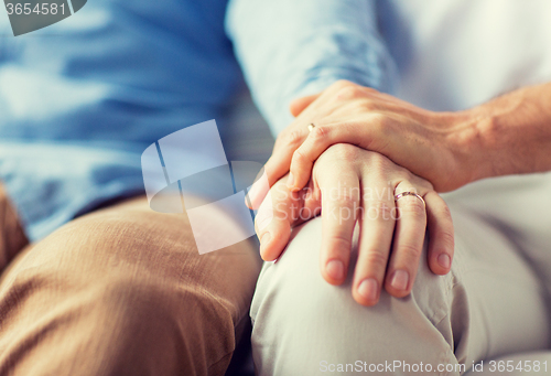 Image of close up of happy male gay couple holding hands