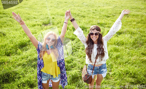 Image of smiling young hippie women dancing on green field