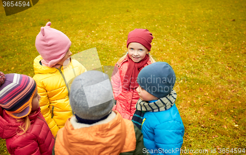 Image of happy children standing in circle at autumn park
