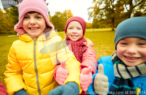 Image of happy children showing thumbs up in autumn park