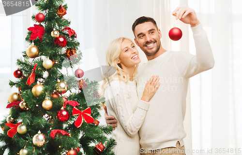 Image of happy couple decorating christmas tree at home