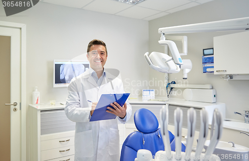 Image of happy male dentist with clipboard at dental clinic