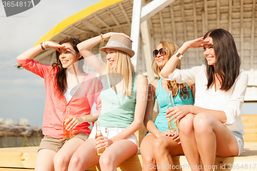 Image of smiling girls with drinks on the beach