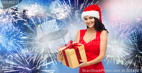Image of happy woman in santa hat with gift over firework