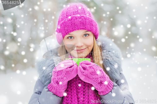 Image of smiling young woman with cup in winter forest