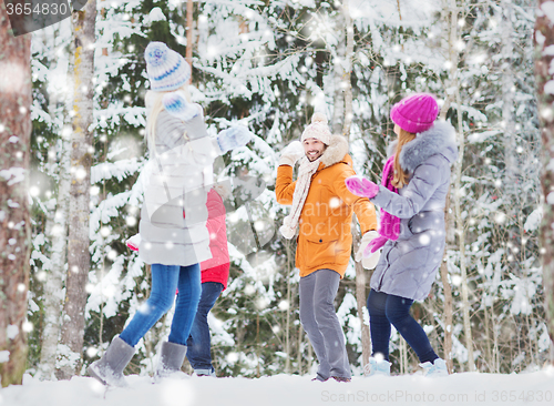 Image of group of happy friends playing snowballs in forest