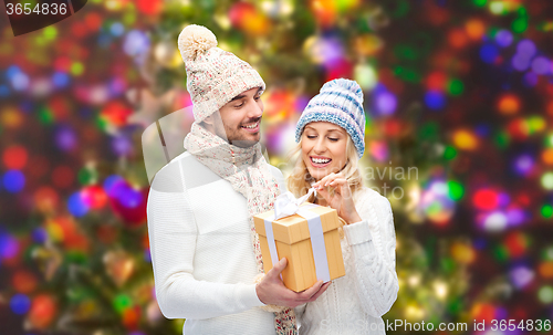 Image of smiling couple in winter clothes with gift box