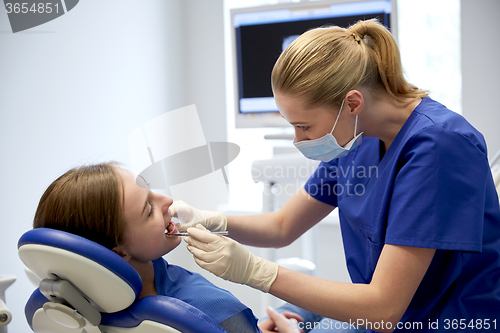 Image of female dentist checking patient girl teeth