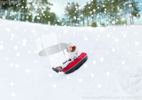 Image of happy teenage girl sliding down on snow tube