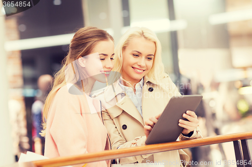 Image of happy young women with tablet pc and shopping bags