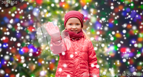 Image of happy little girl waving hand over christmas snow