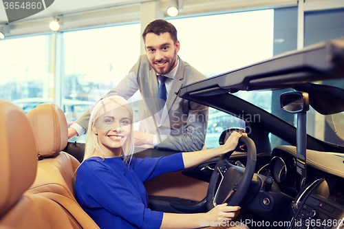 Image of happy couple buying car in auto show or salon