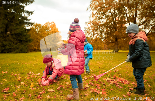 Image of group of children collecting leaves in autumn park