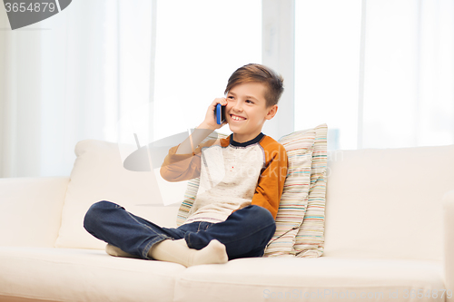 Image of happy boy calling on smartphone at home