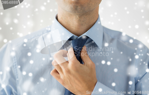 Image of close up of man in shirt adjusting tie on neck